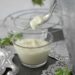 Glazen pot met zelfgemaakte yoghurt en een houten lepel op tafel